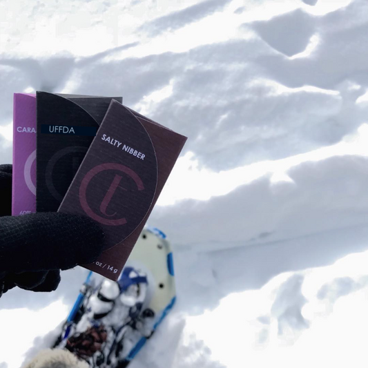 Three TC Chocolate bars held by someone snowshoeing in Minnesota.